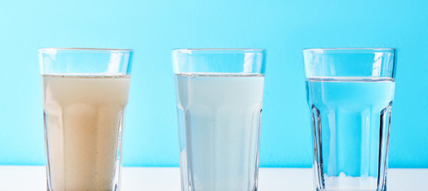 Water filters. Concept of three glasses on a white blue background. Household filtration system.